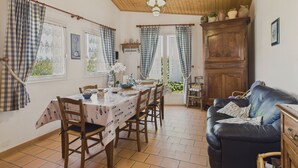 A dining area with a table set for four, wooden chairs, and a blue sofa. - House in Les Conches, garden, sleeps 4 (Longeville-sur-Mer)