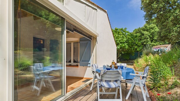 A modern house with a deck, outdoor seating, and a large glass door leading to a patio. - House in Les Conches, garden, sleeps 4 (Longeville-sur-Mer)