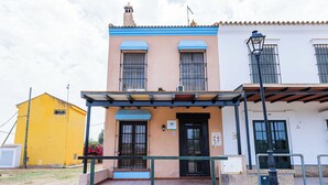 Un edificio con toldo azul, puerta negra y un pequeño espacio exterior con barandilla de metal.