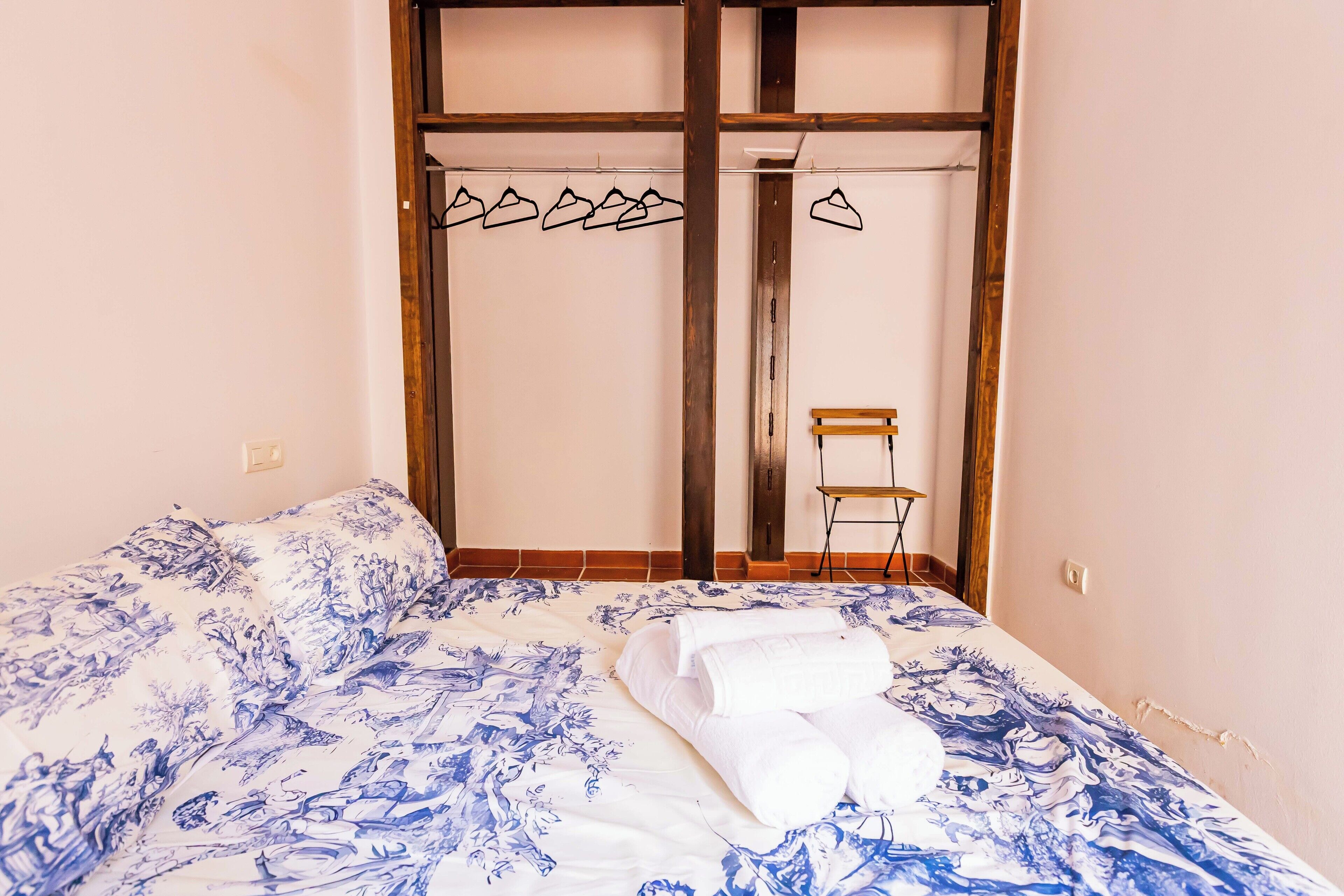 Ein Schlafzimmer mit einem Bett, einem Sessel und einem Kleiderschrank mit Spiegel.