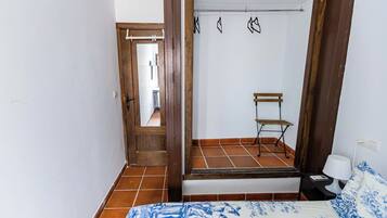 Un dormitorio con una cama, un armario de madera, una mesita de noche con lámpara y una silla.