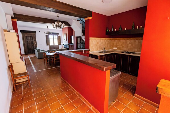 Una cocina con paredes rojas, una isla de madera y piso de baldosas.