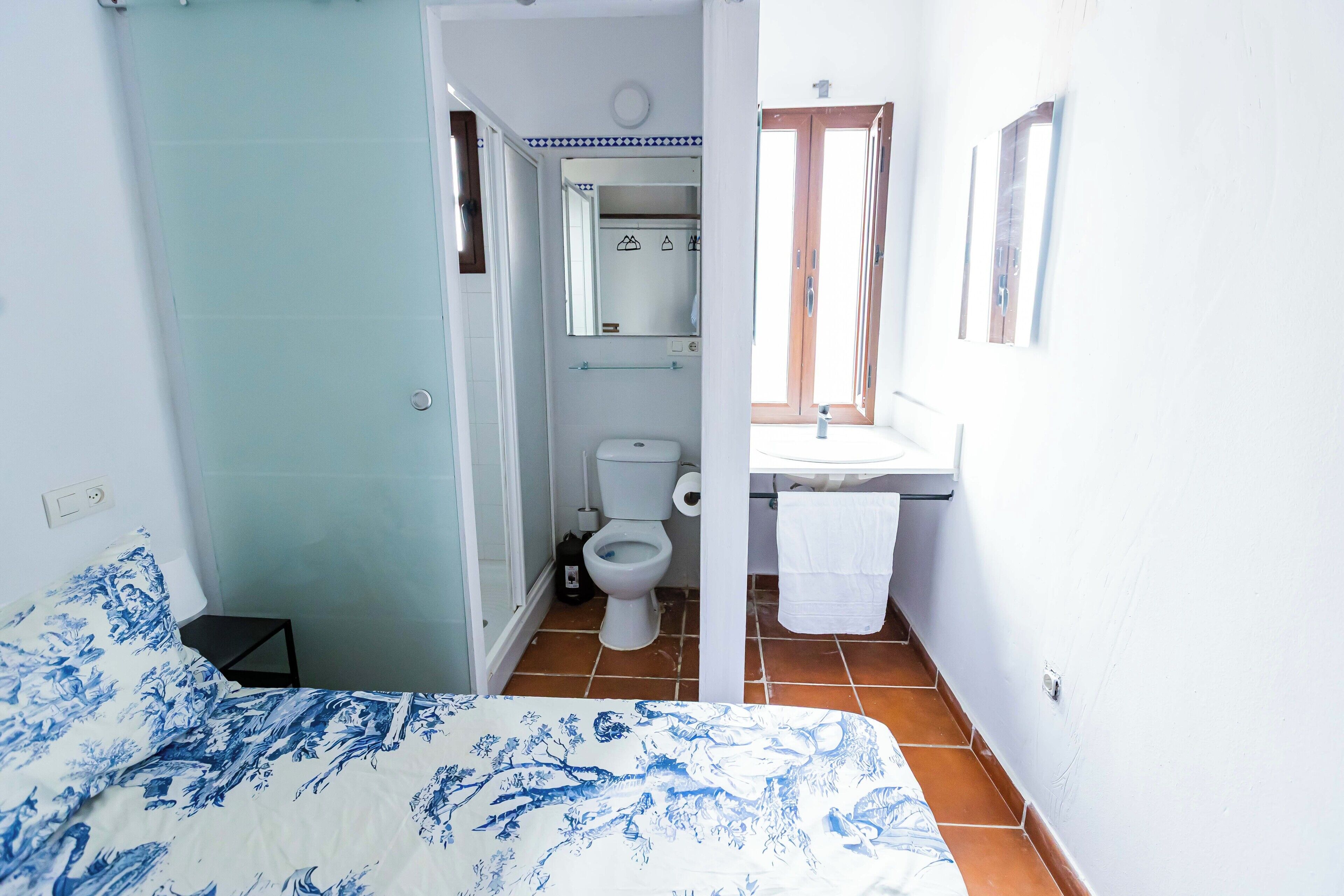 A bedroom with a bed, a bathroom with a toilet, and a sink.