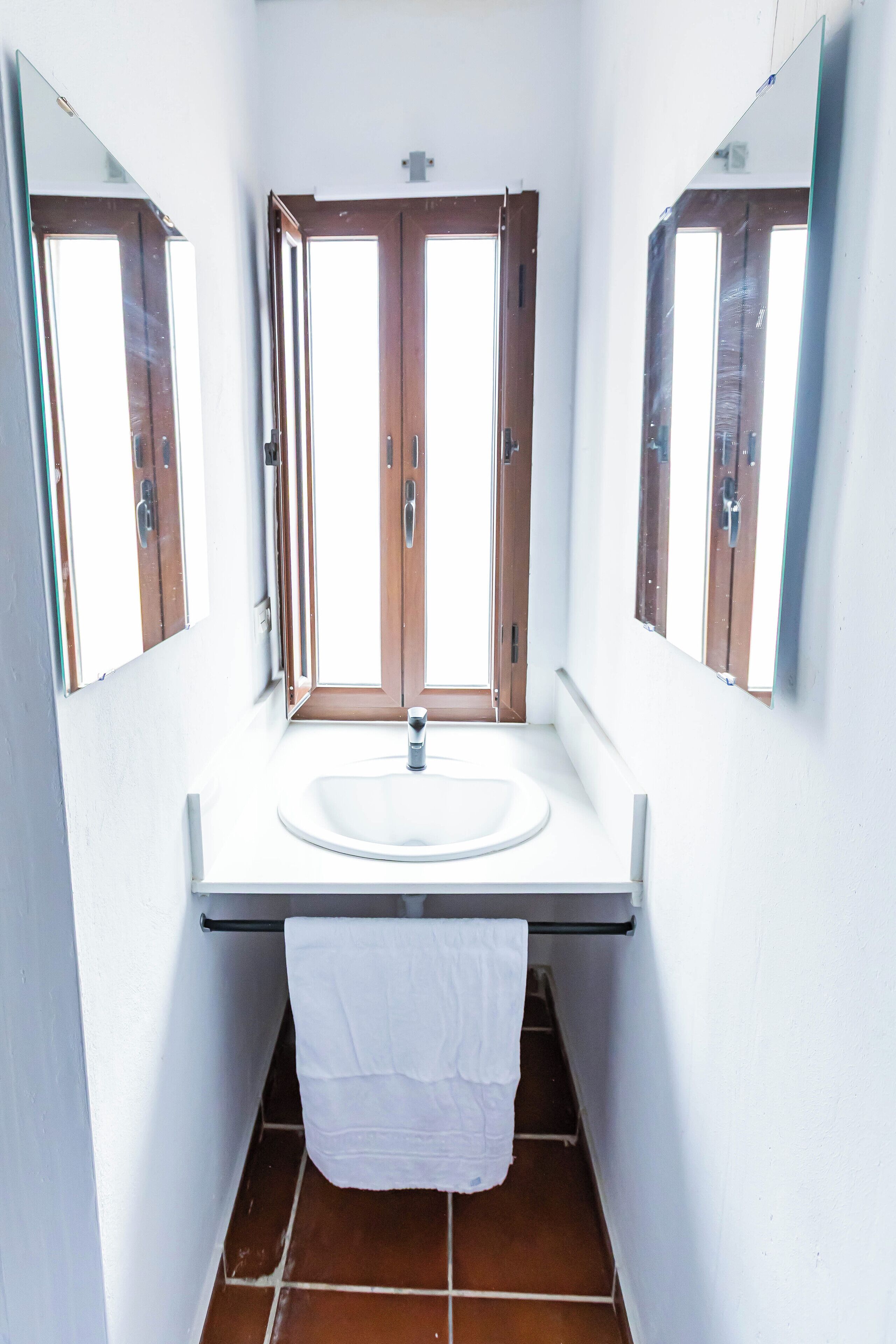 Un bagno con un lavandino bianco, due porte in legno e uno specchio sopra il lavandino.