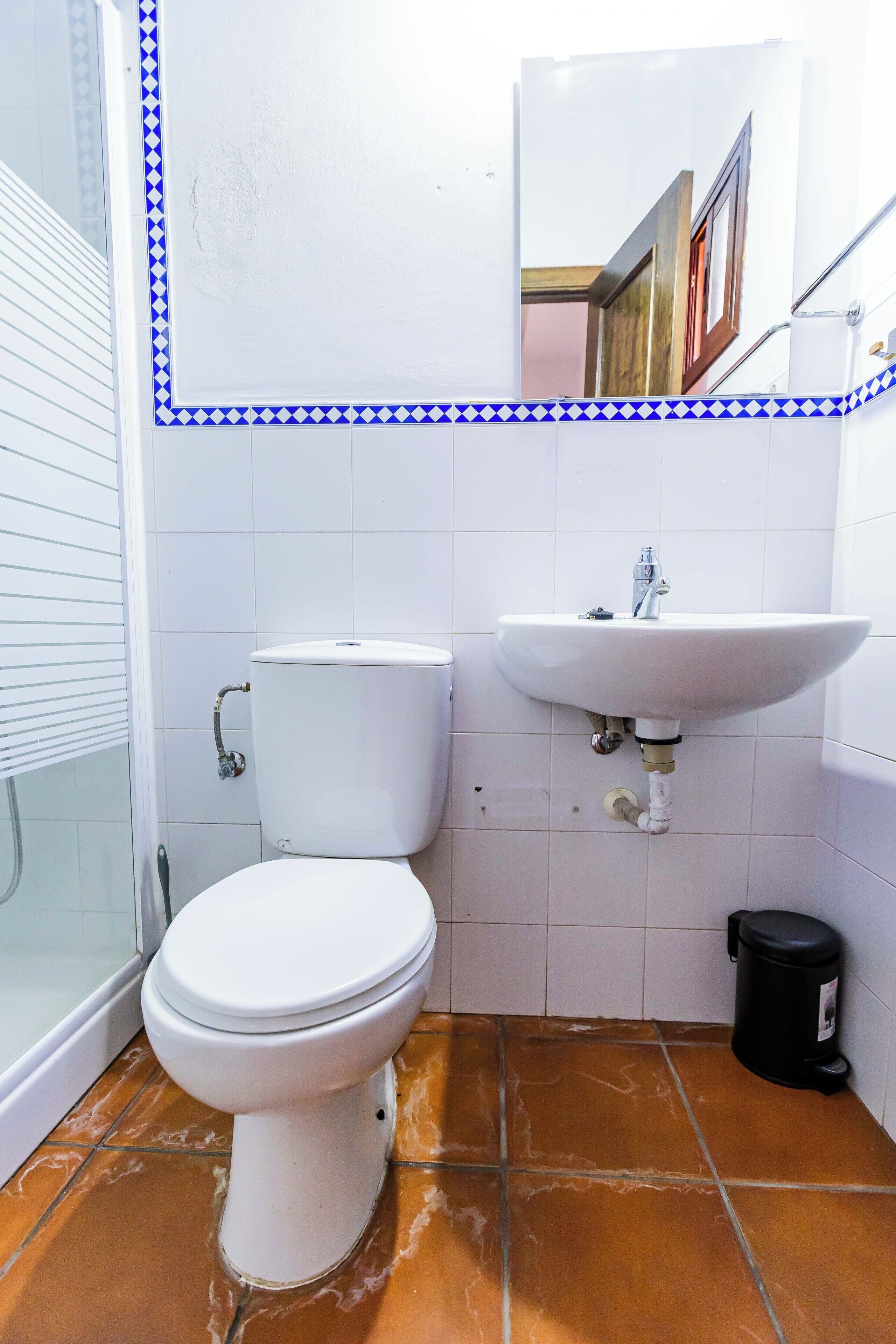 Une salle de bain équipée de toilettes, d’un lavabo et d’une poubelle.