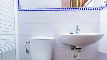 Une salle de bain équipée de toilettes, d’un lavabo et d’une poubelle.