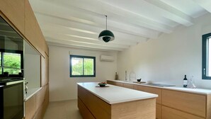 A modern kitchen with wooden cabinets, a central island, and a pendant light. - Lacanau lake and forest, large air-conditioned family house (Lacanau)