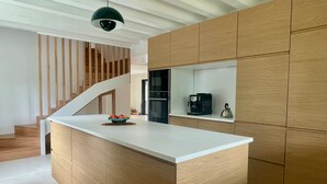 A modern kitchen with wooden cabinetry, a white countertop, and a built-in stove. - Lacanau lake and forest, large air-conditioned family house (Lacanau)