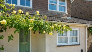 Ein Haus mit grüner Tür, Ziegelaußenwand und Fenster mit weißem Rahmen.