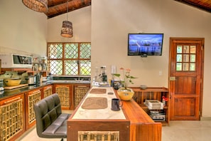 A kitchen with a wooden island, a television mounted on the wall, and a window with a view of a cityscape.