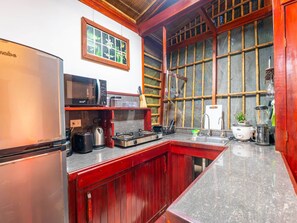 Eine kleine Küche mit Kühlschrank, Mikrowelle, Herd und Spüle.
