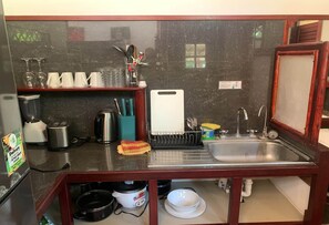 A compact kitchen with a sink, a toaster, a kettle, and a coffee machine.