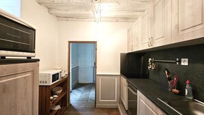 Een keuken met houten kasten, een magnetron en een zwart aanrecht.