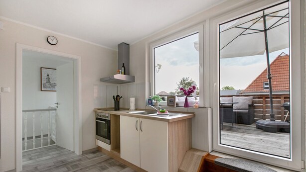 Eine moderne Küche mit Einbauofen, Spüle und Fenster mit Blick auf eine Terrasse.