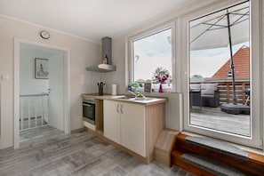 Une cuisine moderne dotée d’un four encastré, d’un évier et d’une fenêtre donnant sur une terrasse.