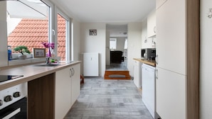 Eine schmale Küche mit Fenster, Heizkörper und Mikrowelle.