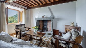 A cozy living room with a fireplace, wooden furniture, and a view of the outdoors. - Casa Bandoni, Bagni di Lucca, Lucca and Viareggio (Bagni di Lucca)