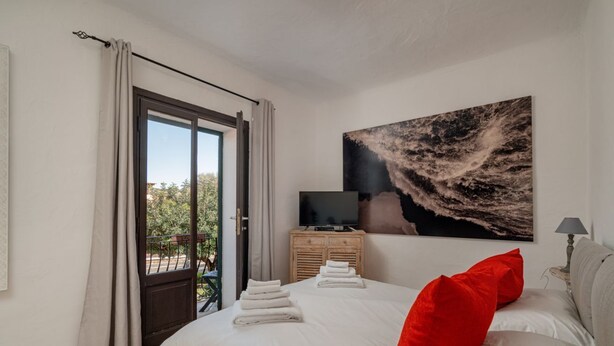 Een slaapkamer met een bed, een televisie op een houten kast en een groot abstract schilderij aan de muur.