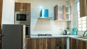 A kitchen with wooden cabinets, a built-in microwave, a gas stove, and a blender. -  1-bedroom apartment with WiFi, fitness room in amazing Accra (Accra)