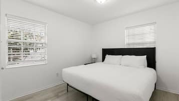 Ein Schlafzimmer mit einem großen Bett, weißen Wänden und einer Deckenleuchte.