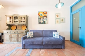 A living room with a blue sofa, a wooden cabinet with glass doors, and a blue door.