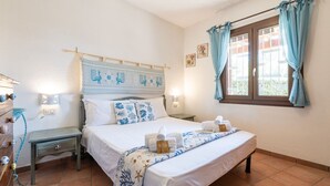 A bedroom with a bed, bedside tables, a window with curtains, and wall-mounted lights. - Villa Aurora - Villasimius Paradise (Villasimius)