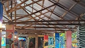 An indoor seating area with red and black checkered sofas, a wooden table, and a metal ceiling structure. - Ibrahim Garden Hostel (Arusha)