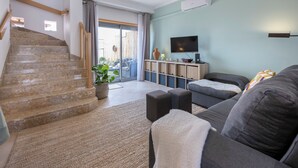 Un salon moderne avec un escalier, un téléviseur à écran plat et un canapé.