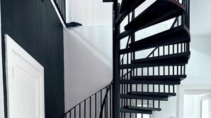 Un escalier moderne avec une rampe en métal noir menant à l’étage supérieur.