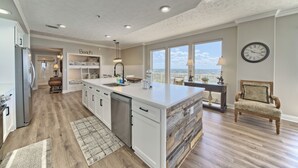 A modern kitchen with a large island, white cabinetry, and a view of the city.