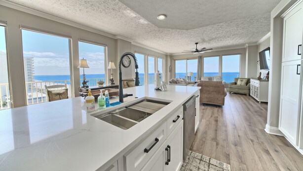 A spacious kitchen with a large island, white cabinetry, and a view of the ocean.