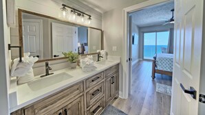 A modern bathroom with a large mirror, dual sinks, and wooden cabinetry.