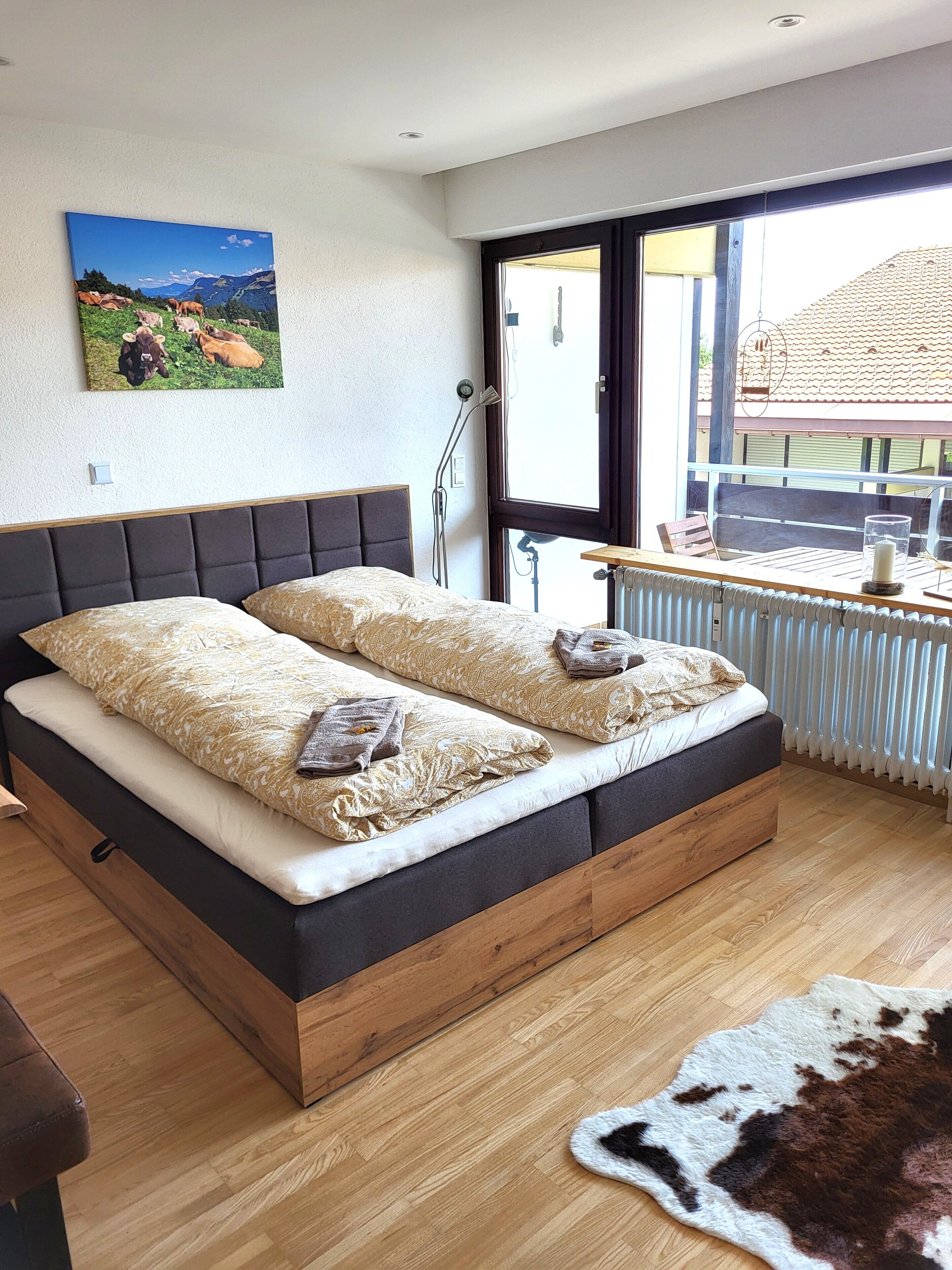 A modern bedroom with a large bed, a view of the outdoors, and a radiator.