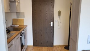 A compact kitchen with wooden cabinets, a built-in oven, and a countertop with a kettle. - Vacation apartment zum Hochgrat (Oberstaufen)