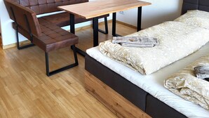 A compact room with a wooden dining table, a bench, and a bed with patterned bedding. - Vacation apartment zum Hochgrat (Oberstaufen)