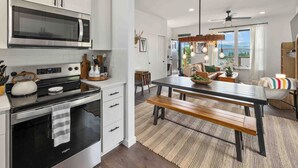 A modern kitchen with stainless steel appliances, a wooden bench at the center, and a view of the outdoors through large windows. - Affordable Secret w/ Charm + PetFriendly/Spa/Views (Ronald)