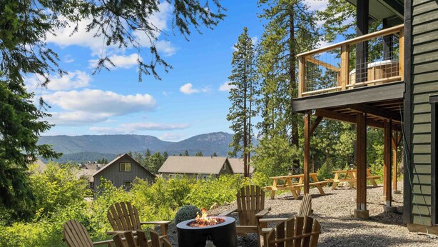 A deck with Adirondack chairs and a fire pit, overlooking a lake and mountains. - Affordable Secret w/ Charm + PetFriendly/Spa/Views (Ronald)