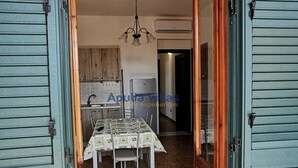Zona pranzo con tavolo imbandito per quattro persone, un lampadario e una cucina sullo sfondo.