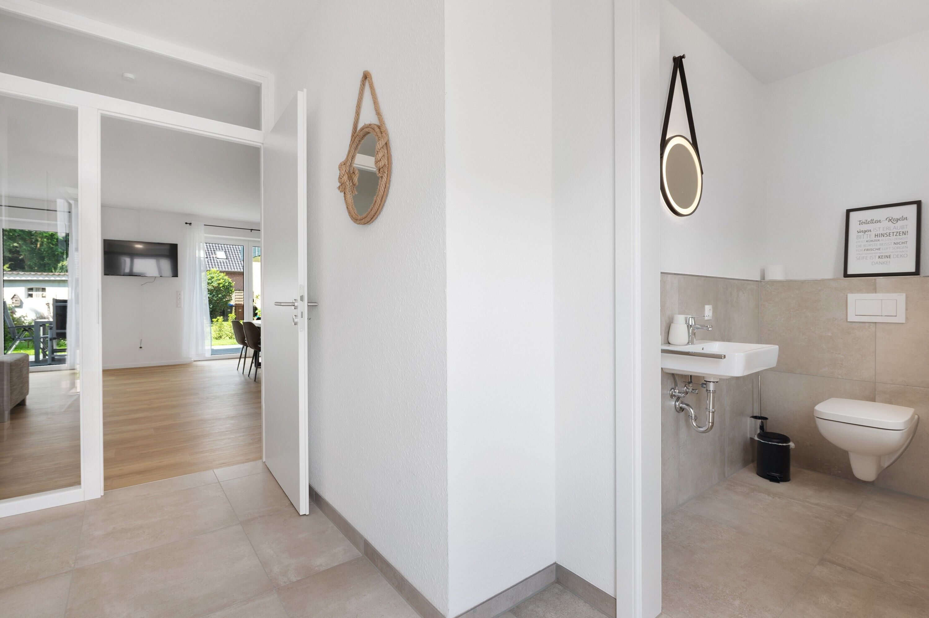 Een moderne badkamer met een wastafel, toilet en een lijst met een bordje erop.