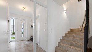 A staircase leading to an upper floor, a door with a glass panel, and a hallway with tiled flooring. - Holiday Home 'Das Strandhaus' with Private Terrace, Private Garden and Wi-Fi (Lembruch)