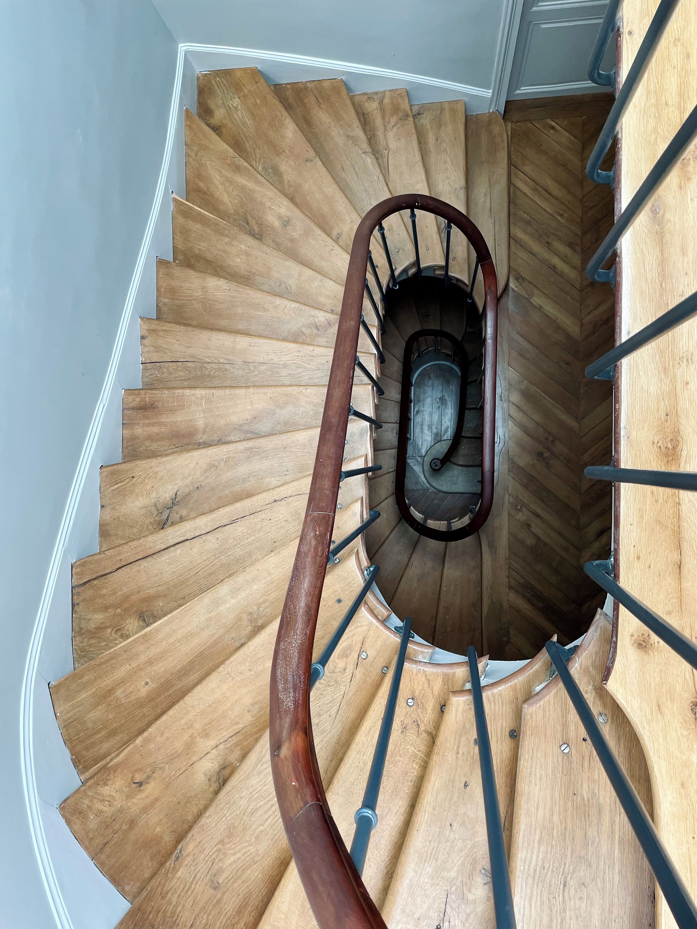 A wooden spiral staircase with metal handrails, leading to an upper floor.