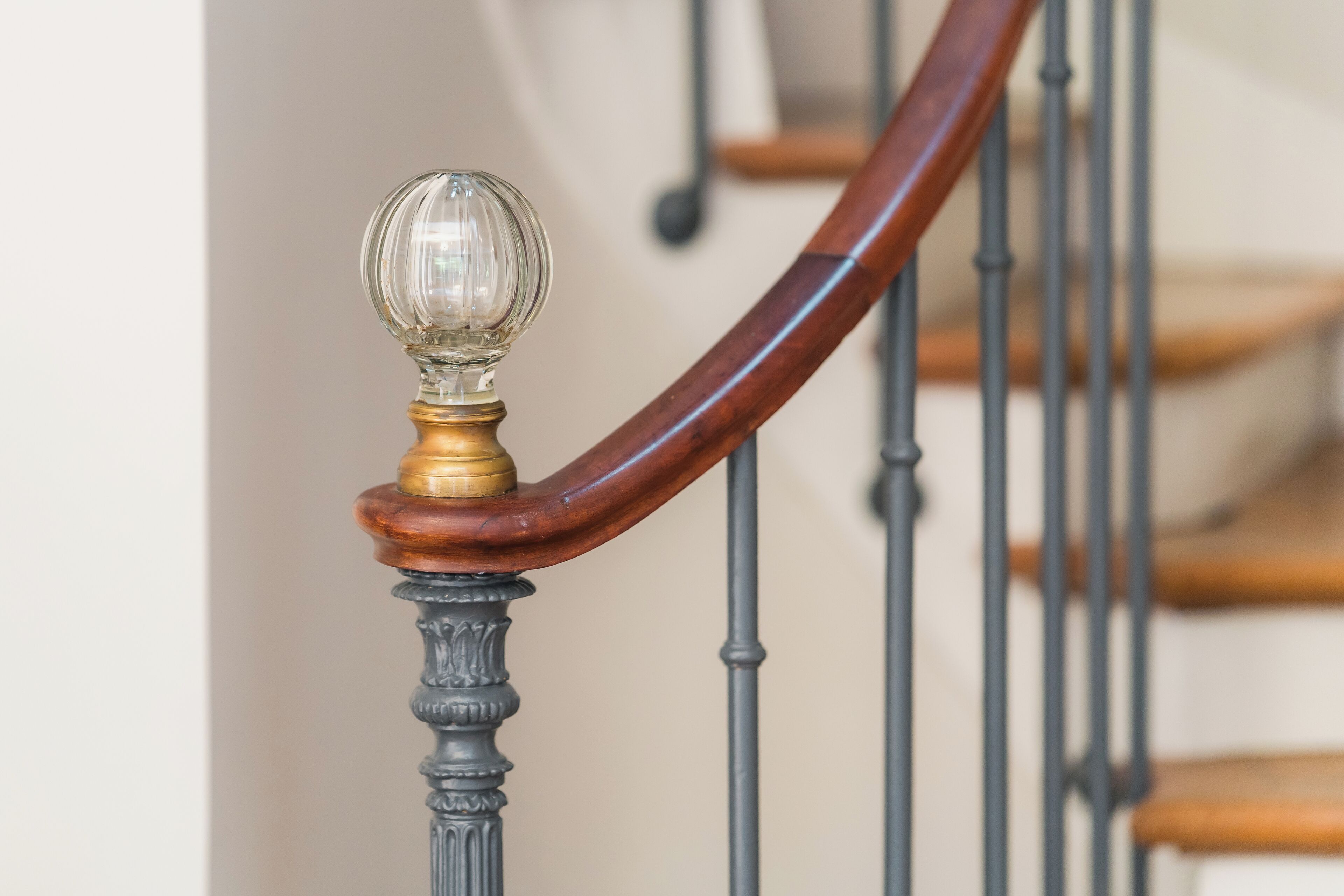 A staircase with a wooden handrail and a glass globe ornament.