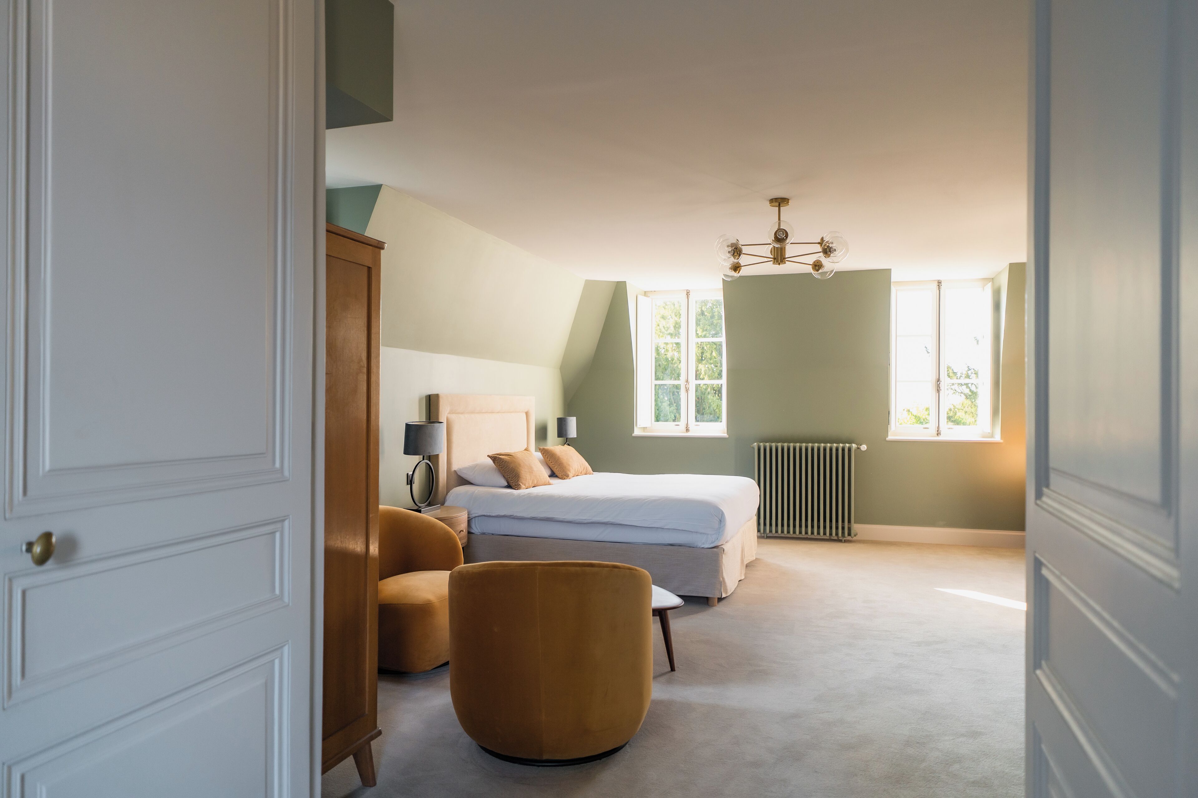 A bedroom with a bed, a chair, a lamp, and a radiator.