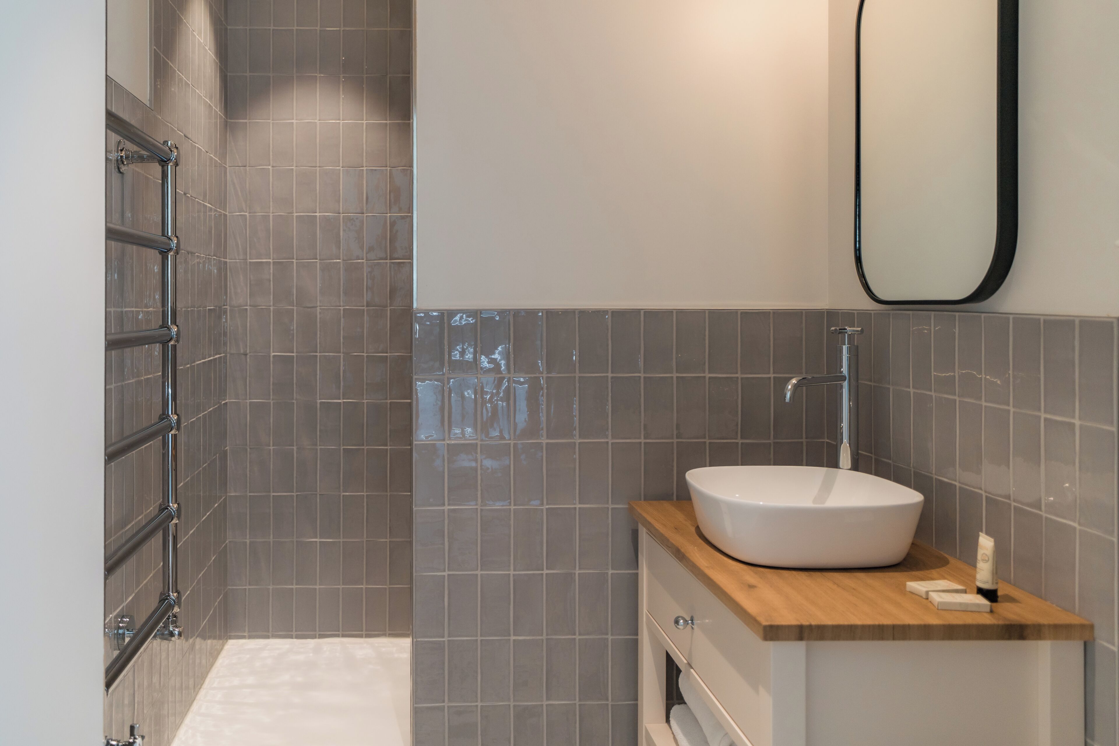 Een moderne badkamer met een groot bad, een houten wastafelmeubel en een spiegel bevestigd aan de muur.