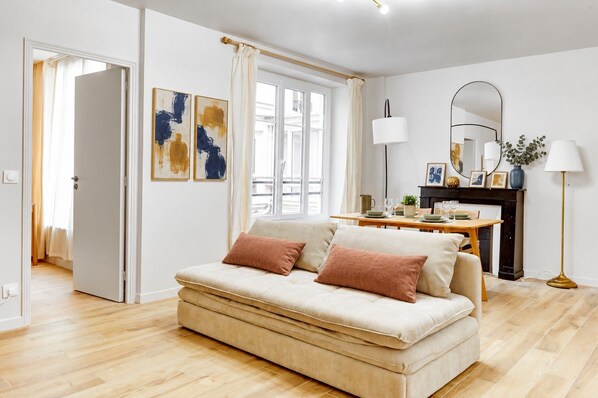 A modern living room with a sofa, a dining table, and a fireplace.