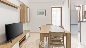Uma sala de estar moderna com televisão de tela plana, mesa de jantar de madeira e cadeiras.