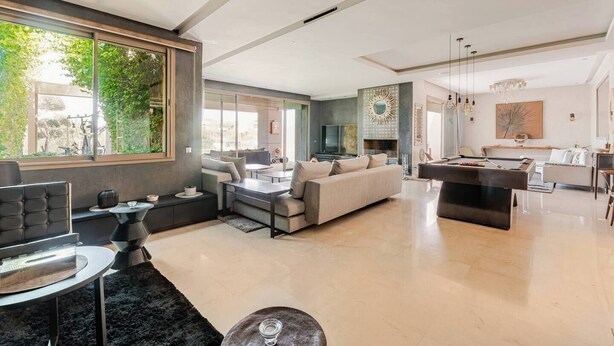 A spacious living area with a sofa, coffee table, and a pool table.