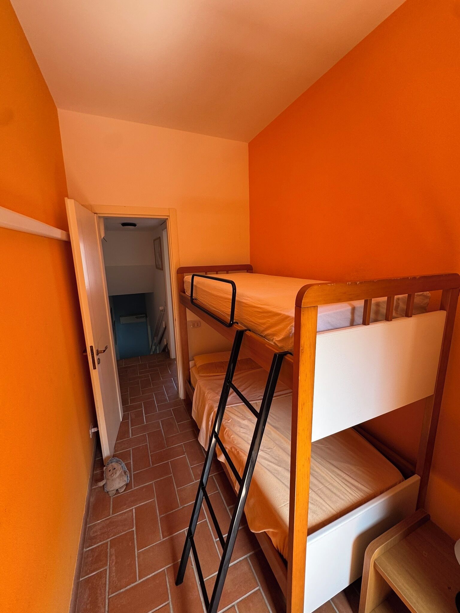 Un dormitorio con literas, una puerta que da a otra habitación y suelo de baldosas.