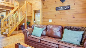 Un interior de madera con un sofá de cuero, una escalera de madera y un cartel que dice 'WELCOME'.