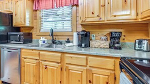 Una cocina con gabinetes de madera, microondas, cafetera y tostadora.